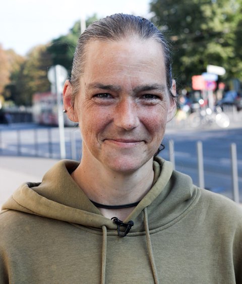 Eine Frau posiert für die Kamera. Sie trägt einen Pullover und lächelt.